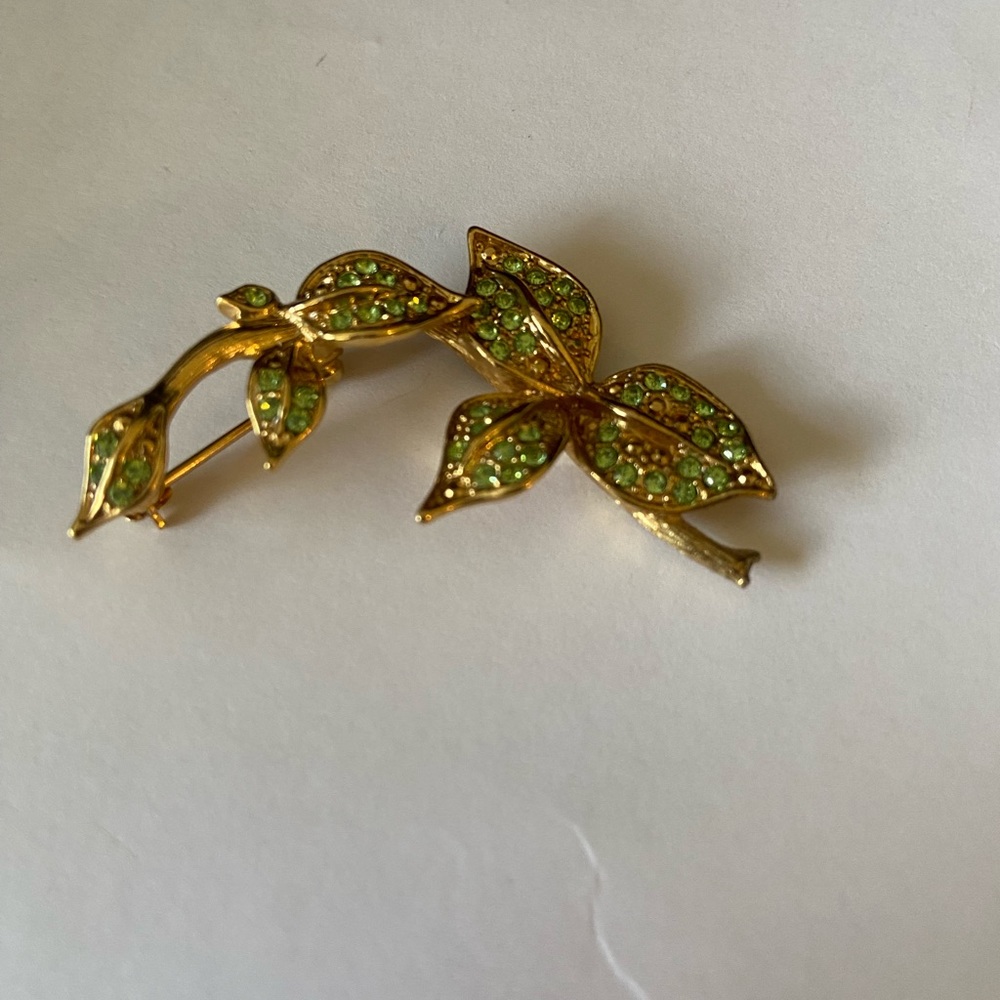 Vintage gold tone pin brooch with green and gold rhinestone leaves on stems